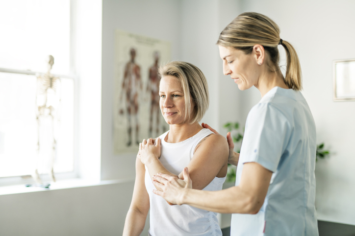 Physiotherapist applying muscle energy technique on female patient's elbow Physiotherapist applying muscle energy technique on female patient's elbow