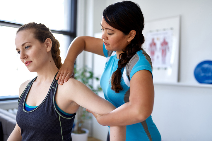 Physiotherapist mobilising shoulder joint of a female patient to treat shoulder pain Physiotherapist mobilising shoulder joint of a female patient to treat shoulder pain