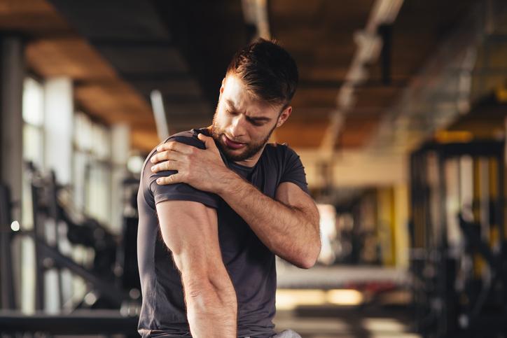 Male athlete with shoulder pain in gym Male athlete with shoulder pain in gym