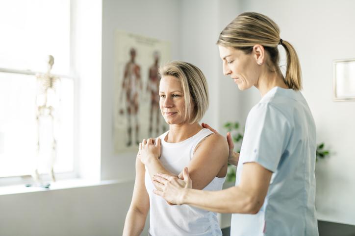 Physiotherapist applying muscle energy technique on female patient's elbow