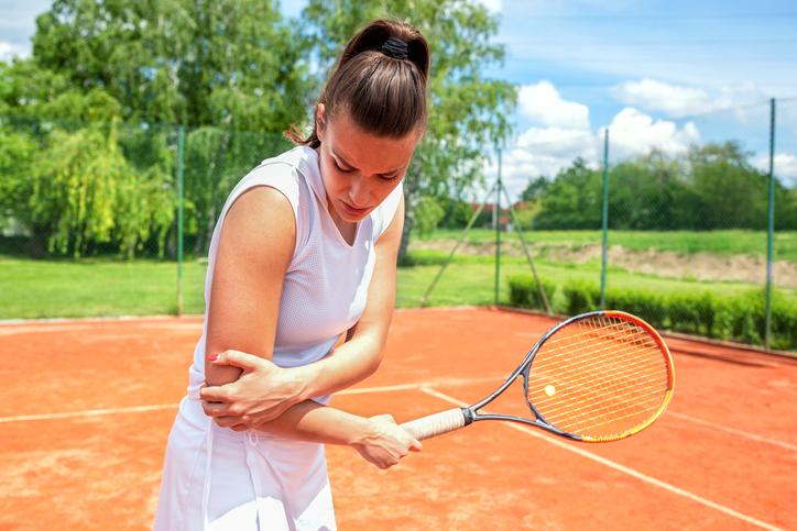Female playing tennis with elbow pain / tennis elbow