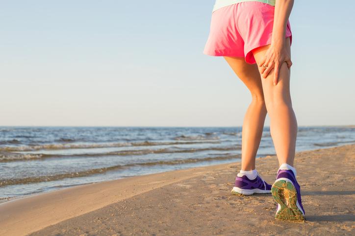 Running girl injured hamstring on beach